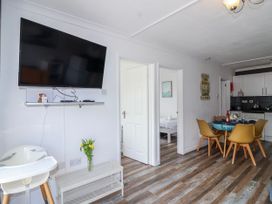 A kitchen with a dining area and a television at Shells Cottage in Looe
