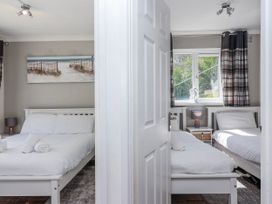 A bedroom with two beds and a window at Shells Cottage in Looe