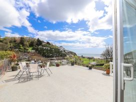 An outdoor terrace with table and chairs by the sea at Shells Cottage in Looe