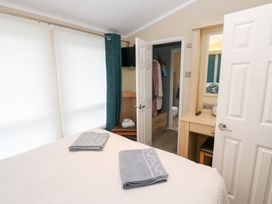 A bedroom with towels on the bed and a door leading to the bathroom at A and C Lodge-Plot 21 Armathwaite