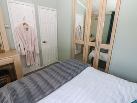 A bedroom with a bed, wardrobe, and robe hanging at A and C Lodge-Plot 21 Armathwaite