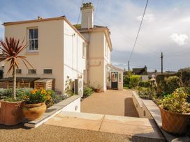 Exterior of a two story cream colored house with a driveway and potted plants Duncombe Teignmouth