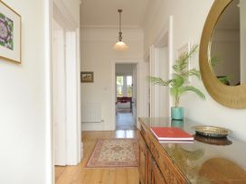 A hallway with a wooden floor rug a wooden cabinet with a plant a red book and a circular mirror at Duncombe Teignmouth