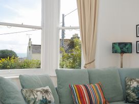 A living room with a light blue sofa and colorful cushions by a window with beige curtains at Duncombe in Teignmouth