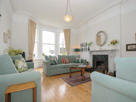 A living room with three sofas a round wooden coffee table a fireplace and large windows at Duncombe in Teignmouth