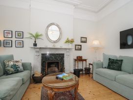 A living room with two sofas a round wooden coffee table a fireplace and a wall-mounted tv at Duncombe in Teignmouth