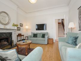 A living room with sofas a coffee table a fireplace and a wall mounted television at Duncombe in Teignmouth