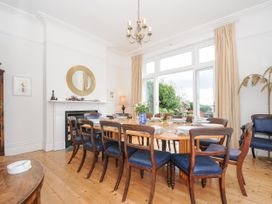 A dining room with a wooden table set with plates and glasses surrounded by wooden chairs with blue cushions at Duncombe in Teignmouth