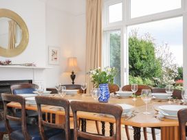 A dining room with a wooden table set with bowls wine glasses and cutlery and a vase of flowers at Duncombe in Teignmouth