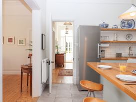 A kitchen with wooden counters stools and a refrigerator next to a hallway and adjoining room at Duncombe in Teignmouth