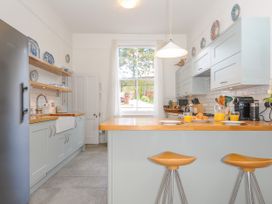 A kitchen with wooden countertops stools plates glasses and orange juice at Duncombe in Teignmouth