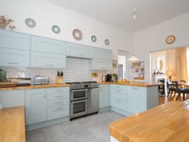 A kitchen with light blue cabinets wooden countertops stove toaster and dining room visible at Duncombe in Teignmouth