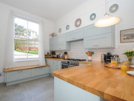 A kitchen with light blue cabinets wooden countertops a large window and breakfast items at Duncombe in Teignmouth