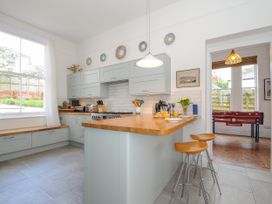 A kitchen with light blue cabinets a wooden countertop and two stools at Duncombe in Teignmouth
