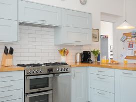 A kitchen with light blue cabinets wooden countertops a stainless steel oven a knife block kettle coffee machine and flowers at Duncombe in Teignmouth