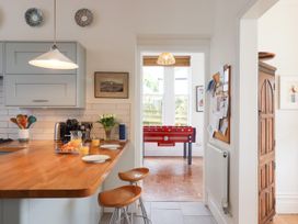 A kitchen with wooden counter stools and a red foosball table in the next room at Duncombe in Teignmouth