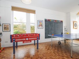 A game room with a foosball table a ping pong table a chalkboard and a dartboard at Duncombe in Teignmouth