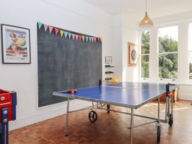 A game room with a ping pong table a dartboard large windows and a blackboard at Duncombe in Teignmouth