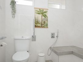 A bathroom with a toilet a gray tiled bench and a wall hanging with a plant image at Duncombe in Teignmouth