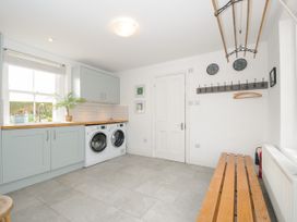 A utility room with washing machines cabinets a wooden bench and a coat rack at Duncombe Teignmouth