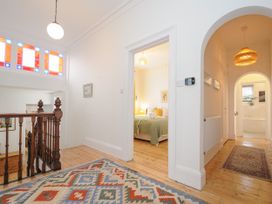 A hallway with wooden floor rugs and a view into a bedroom and bathroom at Duncombe in Teignmouth