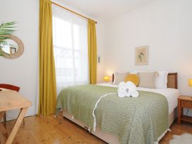 A bedroom with a large bed covered with green bedding and rolled white towels on top at Duncombe in Teignmouth
