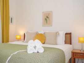 A bedroom with a bed with green blanket and folded white towels with yellow lamps on wooden nightstands at Duncombe in Teignmouth