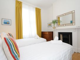 A bedroom with two single beds white linens yellow curtains and a wooden chest of drawers at Duncombe Teignmouth