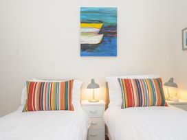 A bedroom with two single beds striped cushions and bedside tables with lamps at Duncombe in Teignmouth