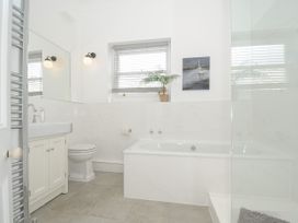A bathroom with a bathtub toilet sink and a window with a plant and a painting at Duncombe in Teignmouth