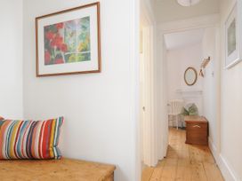 A hallway with wooden floor a white chair a wooden chest and a framed painting at Duncombe in Teignmouth