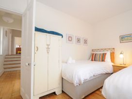 A bedroom with two single beds a wooden wardrobe and three framed pictures on the wall at Duncombe in Teignmouth