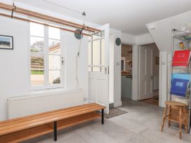 An entryway with a wooden bench a window some shelves with folders and a stool at Duncombe Teignmouth