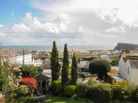 A garden with trees and a gazebo overlooking rooftops and the sea at Duncombe in Teignmouth