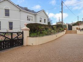 A driveway with a black gate and stone stairs leading to a house with garden beds at Duncombe in Teignmouth