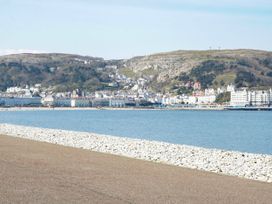 A coastal town with buildings at the base of hills near a pebble beach and a body of water at Yr Angor The Anchor in Llandudno Junction