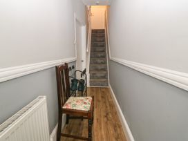 A narrow hallway with a wooden chair with floral cushion and a stairway at Yr Angor The Anchor in Llandudno Junction