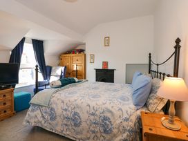 A bedroom with a bed a lamp a TV a chair and a cabinet at Yr Angor The Anchor in Llandudno Junction