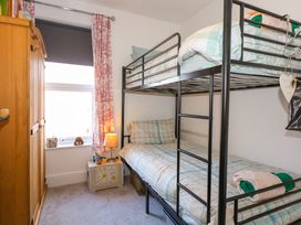A bedroom with a bunk bed a wooden wardrobe a nightstand with a lamp and toys and a window with curtains at Yr Angor The Anchor in Llandudno Junction