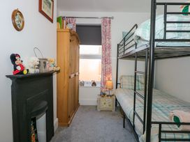 A bedroom with bunk beds wardrobe and a black fireplace with stuffed animals at Yr Angor The Anchor in Llandudno Junction