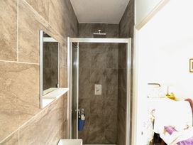A bathroom with a shower enclosure with brown tiles and a mirror next to it at Yr Angor The Anchor in Llandudno Junction