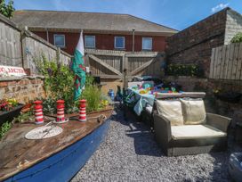 A garden with a boat, table, and chairs at Yr Angor (The Anchor) Llandudno Junction