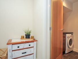 A laundry room with a washing machine and wooden furniture at Whitewater Seaview, Newquay