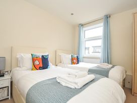 A bedroom with two beds, a lamp, and a window at Whitewater Seaview in Newquay