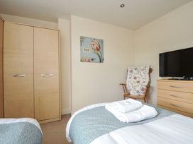 A bedroom with a wardrobe and armchair at Whitewater Seaview in Newquay
