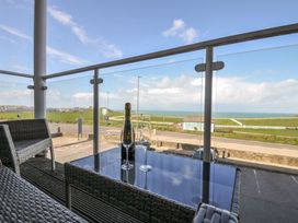 A balcony with wine and glasses overlooking the sea at Whitewater Seaview in Newquay