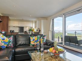 A living room with a kitchen area and outdoor view at Whitewater Seaview in Newquay
