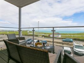 A balcony with a table and chairs overlooking the ocean at Whitewater Seaview in Newquay