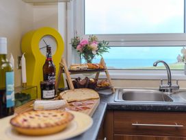 A kitchen with a sink, food items and a view at Whitewater Seaview in Newquay