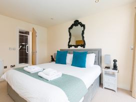 A bedroom with a bed, towels on the bed, and a shower door at Whitewater Seaview in Newquay